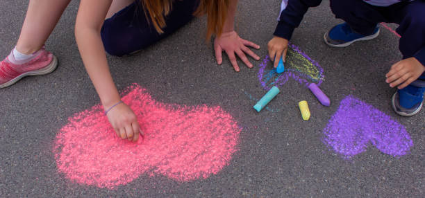 child's hand draws hearts, drawings chalk on asphalt