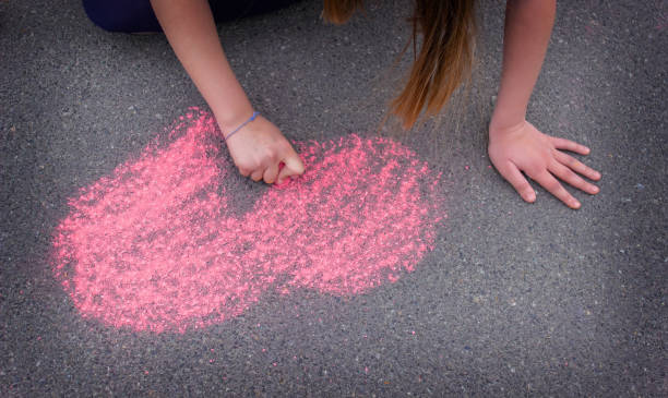 istock child's hand draws hearts, drawings chalk on asphalt 1400263066