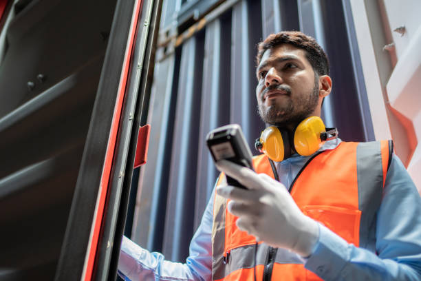 istock Dock worker man in safety vest holding barcode scanner and inspector the quality of container at shipping yard. Import and export product. Manufacturing transportation and global business concept 1400263703