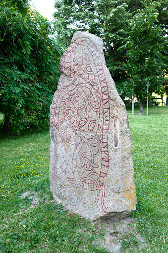A large Viking rune stone engraved with a decorative snake stands watch just outside Foteviken Viking village.