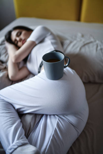 istock Female Placing Coffee Cup On Buttock After Relaxing In Bed At Home 1400264243