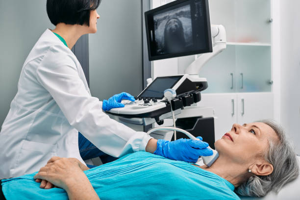 Ultrasound diagnostics of thyroid gland. Endocrinologist making ultrasonography to senior female patient at ultrasound office of medical clinic stock photo
