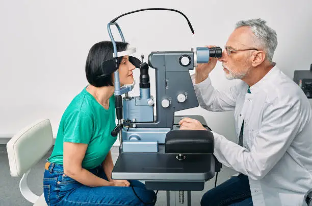Ophthalmology. Woman getting vision test with binocular slit-lamp at ophthalmology clinic with experienced optometrist