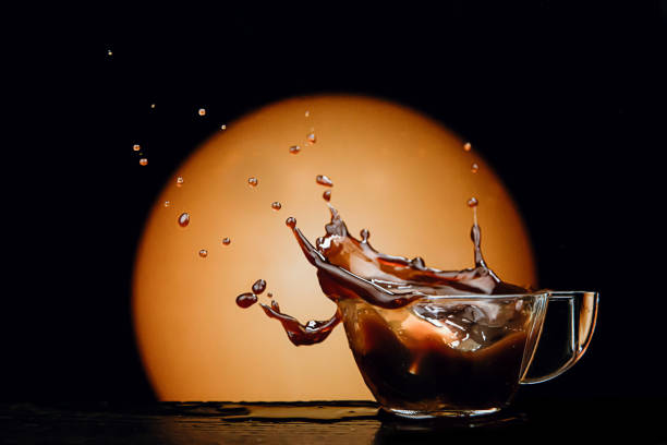 coffee splashed in cup as lump of sugar falls on dark, warm background