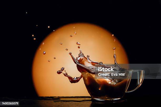 Coffee Splashed In Cup As Lump Of Sugar Falls On Dark Warm Background Stock Photo - Download Image Now