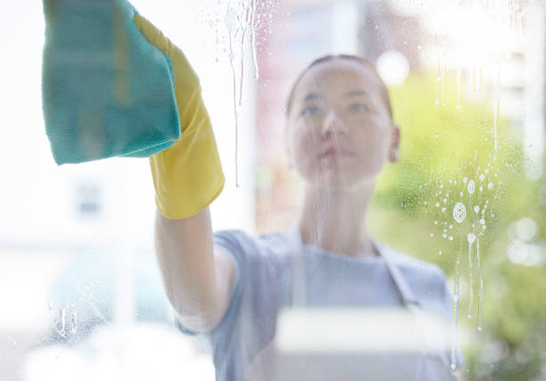 istock A beautiful young mixed race domestic worker using a cloth on a window. One Asian woman enjoying doing chores in her apartment 1400265409