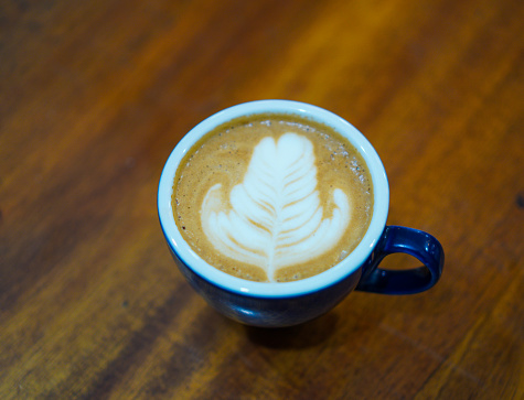 Coffee cup with latte art on wooden background