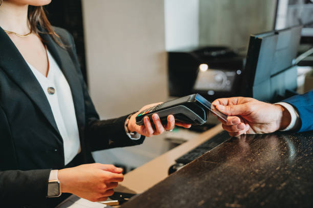 un hombre de negocios está pagando con tarjeta de crédito en la recepción del hotel - edificio de transporte fotografías e imágenes de stock