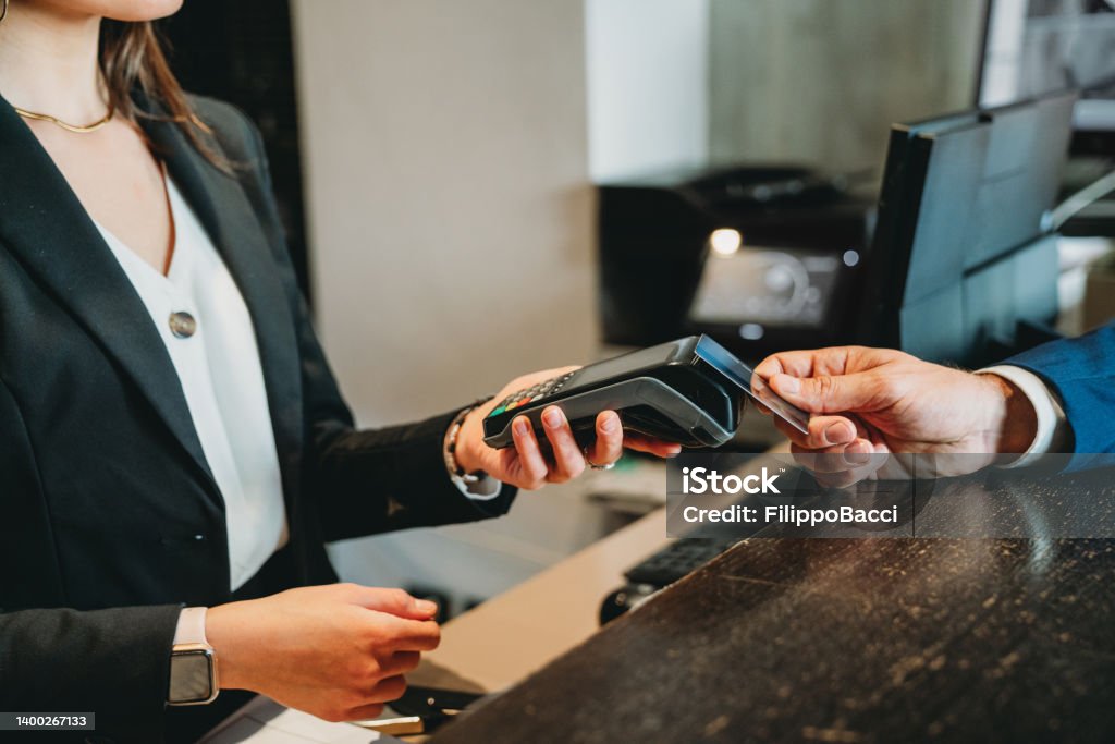 A businessman is paying with credit card at the hotel reception A businessman is paying with credit card at the hotel reception. Detail of the hands. Paying Stock Photo