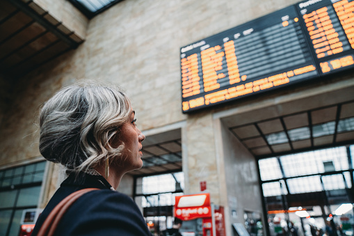 Rear view of a woman checking the arrival departure board in a railroad station