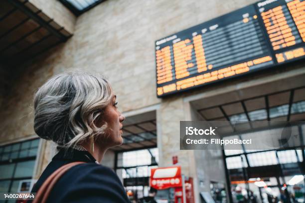 Rear View Of A Woman Checking The Arrival Departure Board In A Railroad Station Stock Photo - Download Image Now