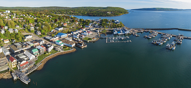 Aerial drone view of a small fishing town & wharf lined with scallop boats.