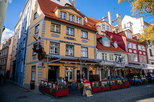 Riga, Latvia, 14 October 2021:  Facade of colorful buildings in historic center of medieval city, renaissance and baroque houses at summer sunny day, cafe with wooden windows at Livu square