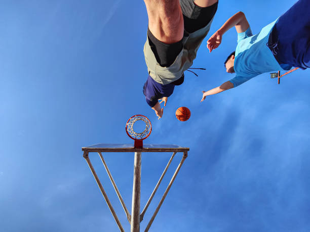 low angle view Asian chinese father and son having fun, playing basketball outdoors during weekend morning