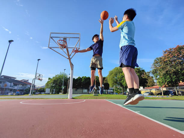 istock backlit Asian chinese father jumping blocking son shooting playing basketball outdoors during weekend morning 1400269227