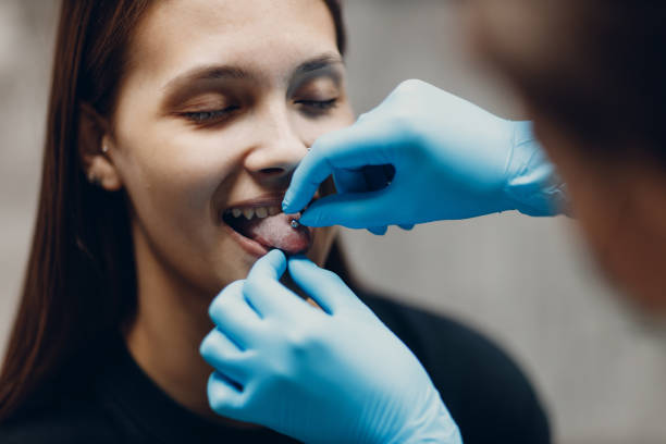 Young woman doing tonque piercing at beauty studio salon. stock photo