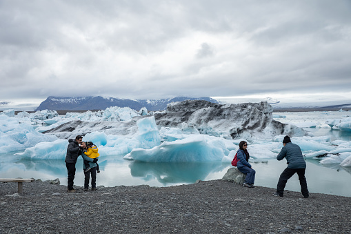 Tourists taking photos at Jokulsarlon, a glacial lagoon in Iceland. Jokulsarlon formed around 1935 and the size of the lake keeps increasing due to the melting glaciers.