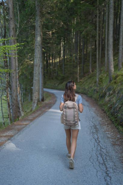 istock Young woman walks along forested road 1400270728