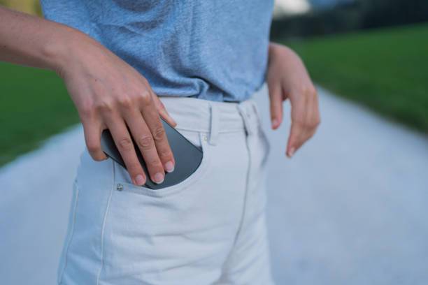 She takes cellphone out of her back pocket, on a summer morning