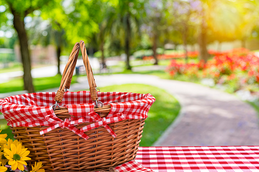 Picnic basket on table with blurred public park background