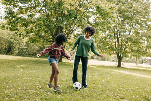 Girl playing soccer with mom in the park
