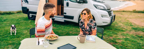 istock Couple sitting outdoors with camper van and beach on background 1400274459