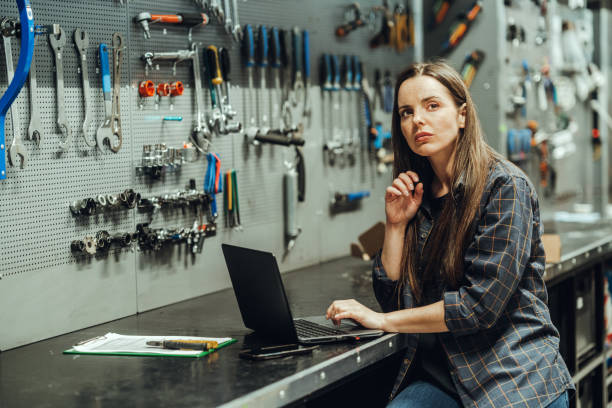 istock bicycle store - Female Bicycle Mechanic with laptop 1400277287
