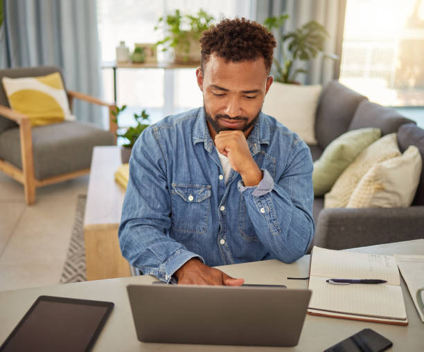 istock Freelance businessman reading an email on his laptop. Remote virtual worker thinking while typing on his computer. Young businessman using a wireless digital device at home 1400280370