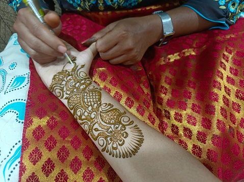 Mehndi artist making mehndi bridal hand In India, mehndi design.