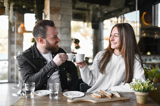 Smiling Couple Enjoying Breakfast And Making Celebratory Toast With Coffee