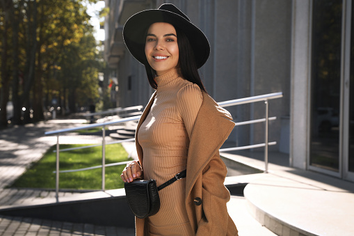 Beautiful young woman with stylish waist bag on city street