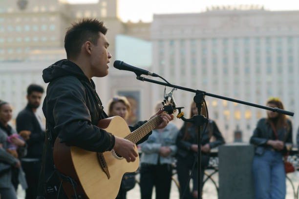 Moscow, Russia - May 21, 2022: People on city street. A man singing song. He playing giutar.  People listening to his performance.  Occupation theme