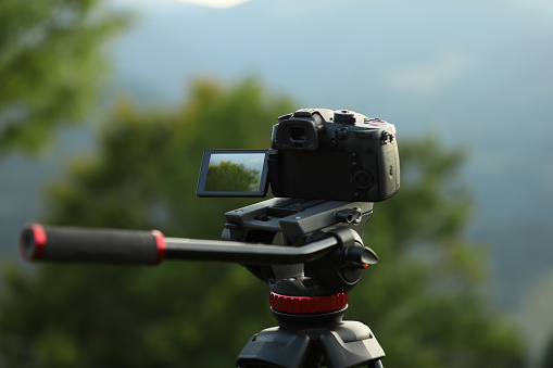 Taking photo of beautiful landscape with camera mounted on tripod outdoors