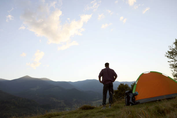 istock Tourist with backpack and sleeping pad near camping tent in mountains 1400286098