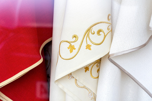 Set of different catholic church priest chasubles, vestments, traditional robes, priest's religious clothing, clothes simple concept, detail, extreme closeup, nobody. Christianity, catholic culture