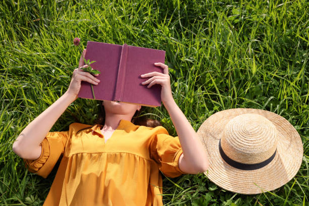 istock Woman reading book on green meadow, above view 1400288887