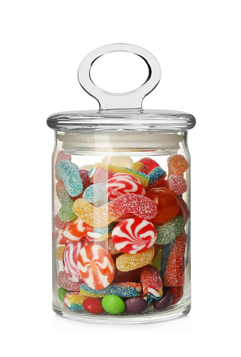 Many different candies in glass jar isolated on white