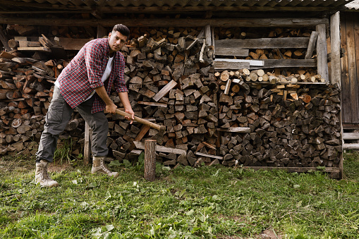 Man chopping wood near log pile outdoors
