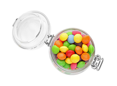 Many tasty candies in glass jar isolated on white, top view