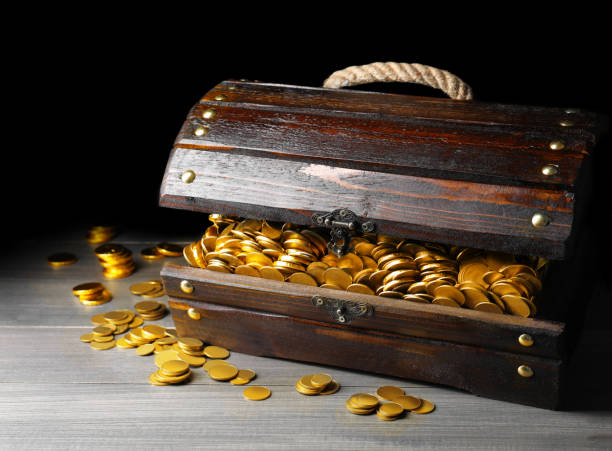 istock Open treasure chest with gold coins on grey wooden table 1400291662