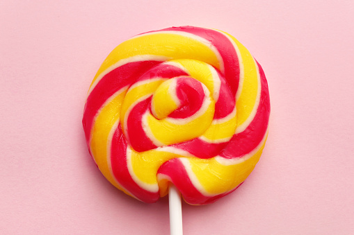 Sweet colorful lollipop on pink background, top view