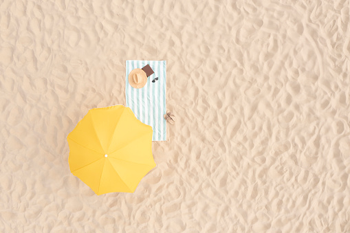 Sombrilla de playa cerca de toalla y otras cosas de turistas en la arena, vista aérea. Espacio para texto photo