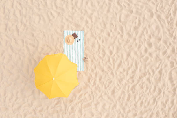 Beach umbrella near towel and other vacationist's stuff on sand, aerial view. Space for text Beach umbrella near towel and other vacationist's stuff on sand, aerial view. Space for text parasol stock pictures, royalty-free photos & images