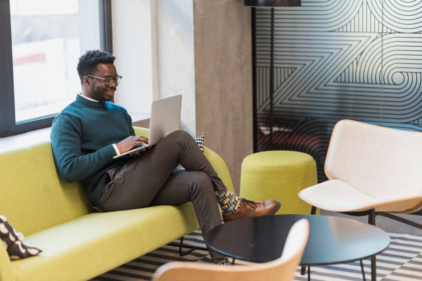 istock Modern young businessman sitting in a lobby, working on laptop 1400293237