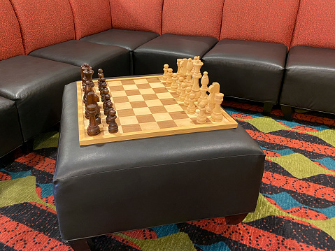 Chess board set with pieces on a leather ottoman ready to play.