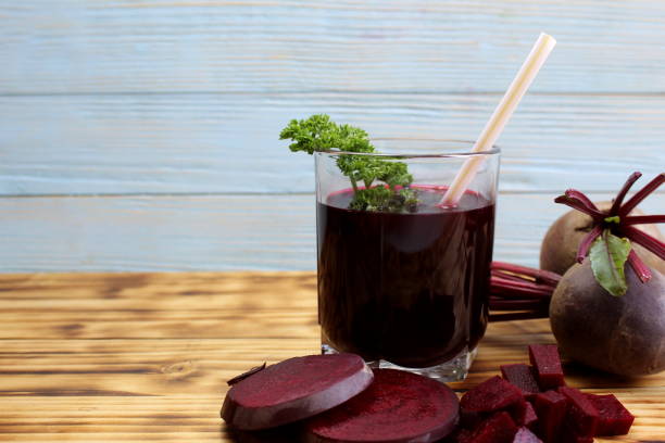 istock Beetroot juice in a glass stands on a wooden table. 1400295727