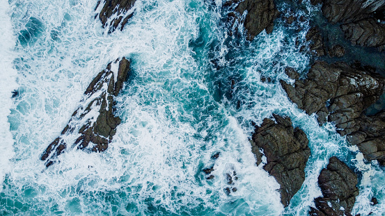 WAVES BREAKING ON ROCKS IN THE SEA OF THE COAST OF THE BASQUE COUNTRY FROM DRONE IN AERIAL VIEW
