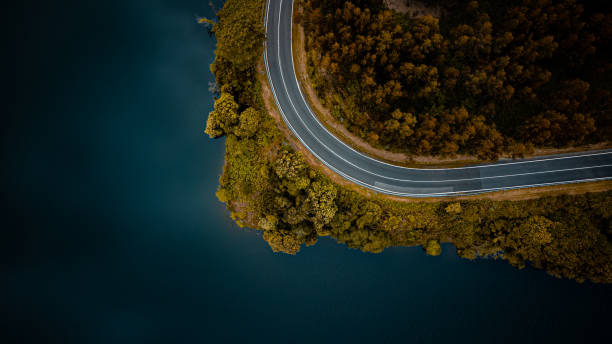 WINDING MOUNTAIN ROAD WITH LAKE FROM AERIAL VIEW WITH DRONE