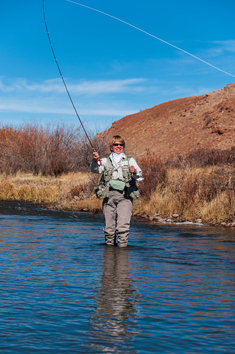 A fisherman is flyfishing in a beautiful River  on a perfekt Day.