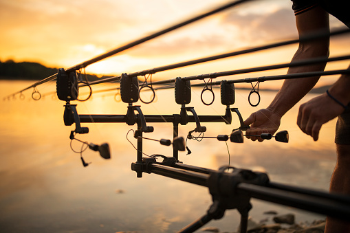 Fisherman on the shore carp fishing on sunset.